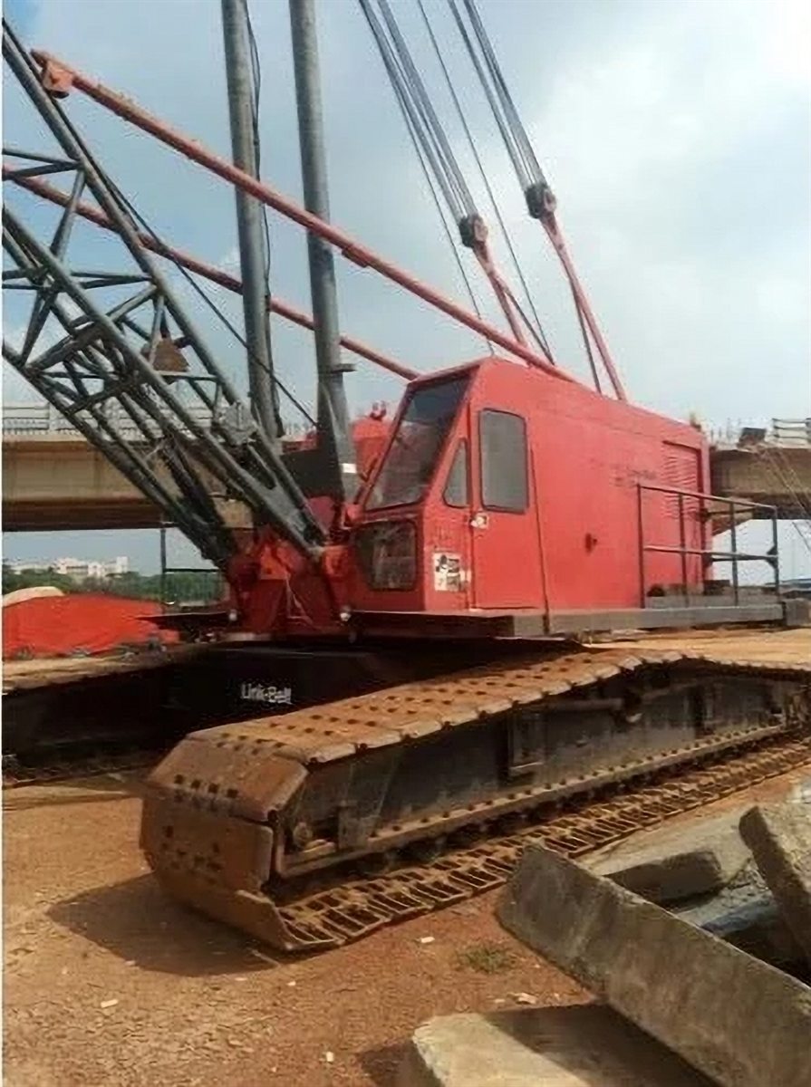 Red Link-Belt crawler crane working beneath a bridge span