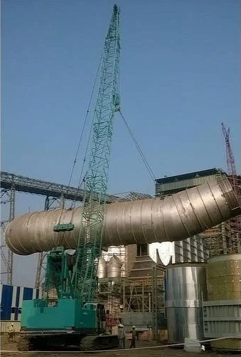 Crawler crane lifting a cylindrical vessel into place at a plant